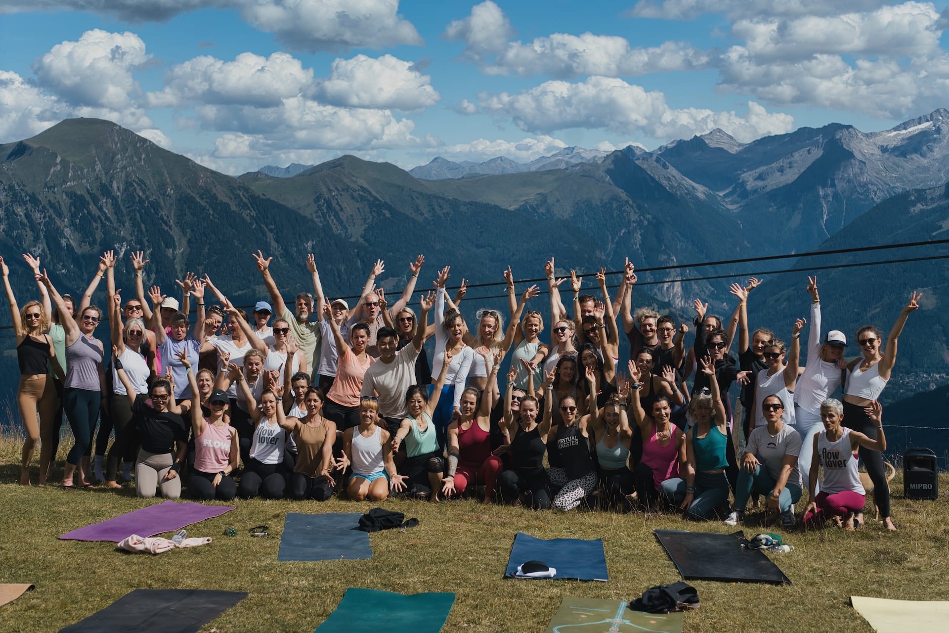 Viele Yogis die im Gruppenbild in den Bergen posen.